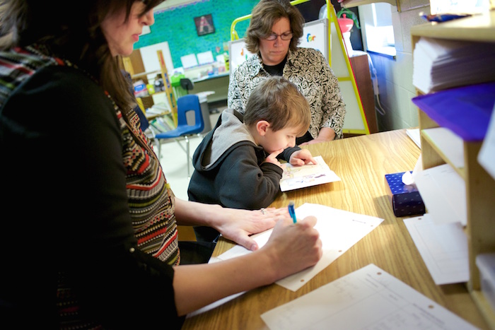 Amber Weidinger, left, and Joanne LeBlanc, center, take notes as six-year-old Caleb Rutkowski starts his 30-minute Reading Recovery session at Lynch Elementary. 
