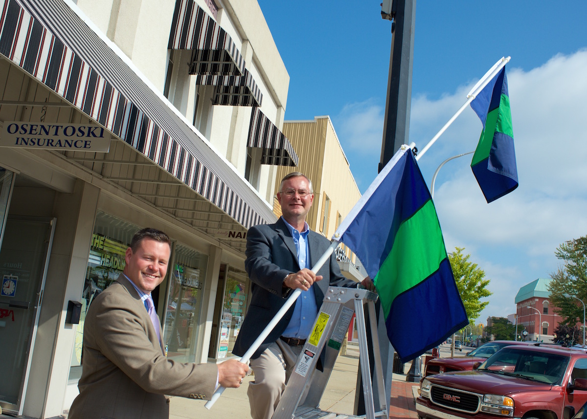 LCS Superintendent Matt Wandrie and Lapeer DBA President Dan Osentoski show off the new Spirit Flags in downtown Lapeer.